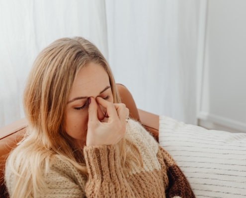 Woman dealing with sinus pressure caused by indoor allergies during winter