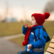 young boy wearing scarf and hat sneezing