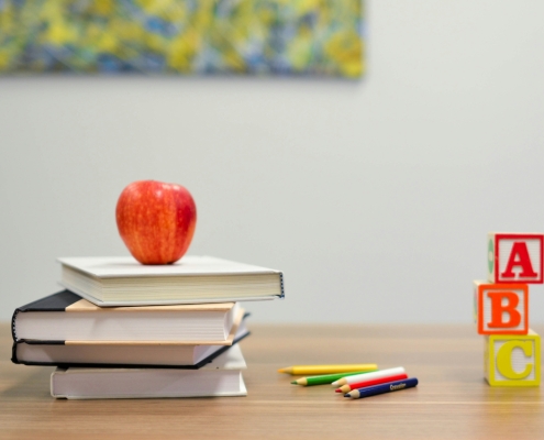 School supplies of apple, books, pencils and blocks sitting on desk