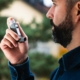 Man managing asthma and allergy symptoms with an inhaler.